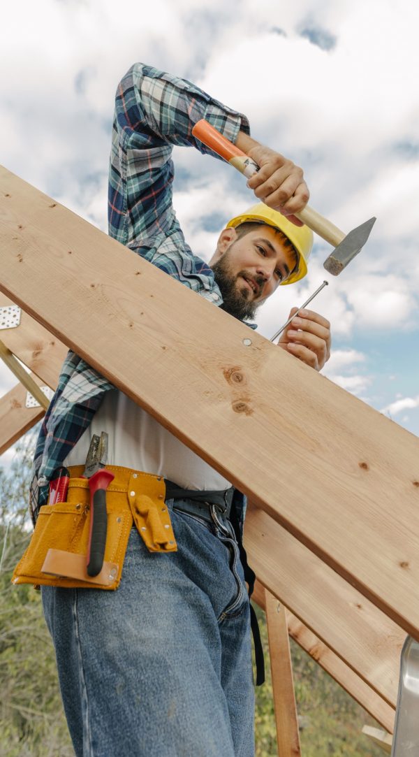 travailleur-de-la-construction-avec-marteau-construisant-le-toit-de-la-maison